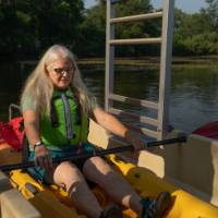 woman in a single kayak using an accessible launch to get onto the water
